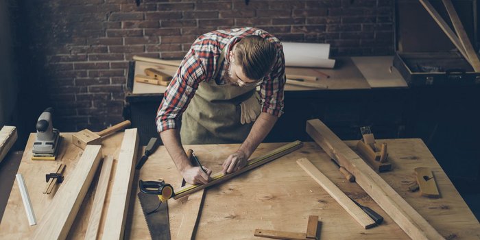 Ein Tischler zeichnet ein Holzbrett an
